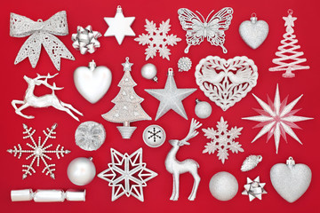Fototapeta na wymiar Silver Christmas bauble decorations on red background. Traditional festive greetings card for the holiday season. 