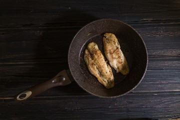 Frying pan with delicious fish on pan wooden background