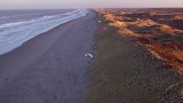 Drone/Aerial shot of a parapenter flying over the duns ot the Netherlands. Shot was made by a professional drone pilot.