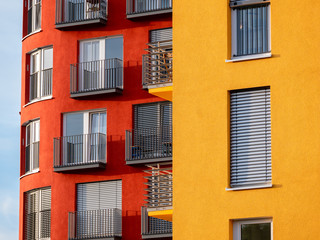 Fototapeta na wymiar Image of two red and yellow high rise buildings with windows and balconies and blinds