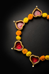 Diwali glowing Diya and flowers arranged in circular shape forming a design with copy space,...