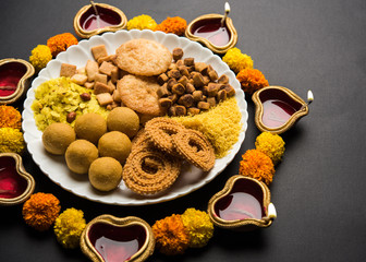 Diwali Rangoli or design made using Indian snacks/sweet and diya or lamp and flowers