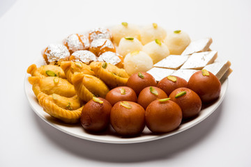 Indian sweets in a plate includes Gulab Jamun, Rasgulla, kaju katli, morichoor / Bundi Laddu, Gujiya or Karanji for diwali celebration