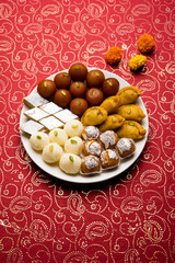 Indian sweets in a plate includes Gulab Jamun, Rasgulla, kaju katli, morichoor / Bundi Laddu, Gujiya or Karanji for diwali celebration