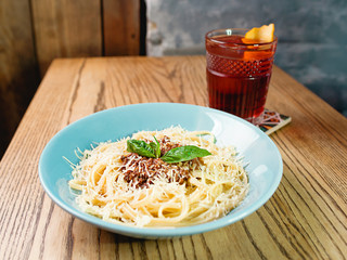 pasta bolognese in the plate and oldfashioned cocktail on the table in the bar