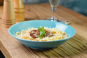 pasta bolognese in the plate, salt and pepper, glass of sparkling dry wine on th table