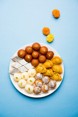 Indian sweets in a plate includes Gulab Jamun, Rasgulla, kaju katli, morichoor / Bundi Laddu, Gujiya or Karanji for diwali celebration