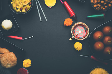 Diwali sweets and snacks arranged in a group with Diya or oil lamp, flowers and Fire Crackers or...