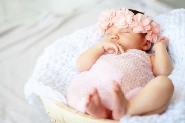Sweet newborn Caucasian baby sleeping. Pink flower head band. New born child photo session.
