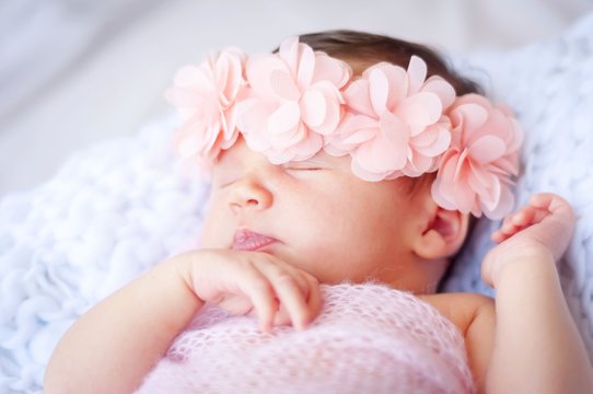 Sweet newborn Caucasian baby sleeping. Pink flower head band. New born child photo session.