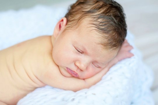 Sweet and innocent infant baby sleeping on a soft white blanket. Newborn photo session.
