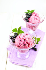 Ice cream with black currant in two glasses on napkin