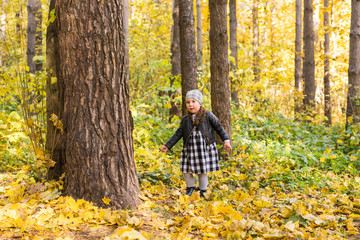 Fall, childhood, people concept - little happy girl walking in autumn park