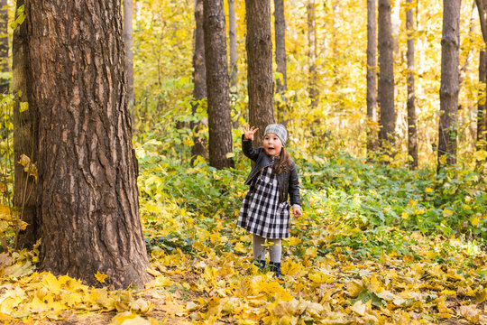 Children, fall, people concept - young child walking in autumn park and keeping yellow leaves