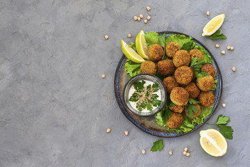 Homemade deep-fried vegetarian  falafel made from ground chickpeas and broccoli,  are laid over a bed of salads .  Middle Eastern food.