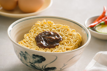 Instant noodles in bowl and vegetable side dishes on stone background. Quick & easy food concept.