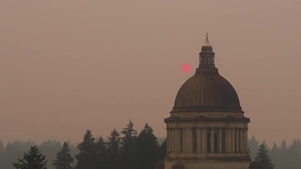 Hazy PNW Wildfire Smoke surrounding Washington Capital in Olympia, USA, telephoto drone tracking shot of the Sun appearing behind the building, Slow Motion