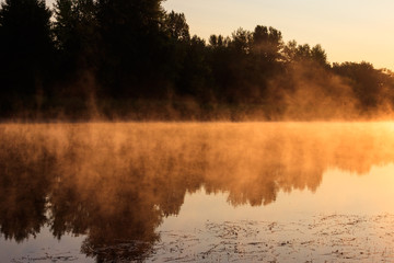 View of river in the mist at sunrise. Fog over river at morning