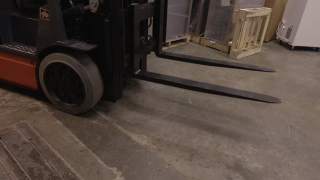 Blue Collar Worker Lowering the Forks of an Electric Fork Lift