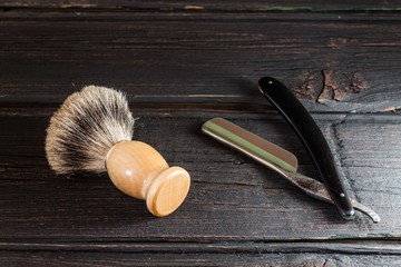 Straight razor and shaving brush on a luxury wooden background