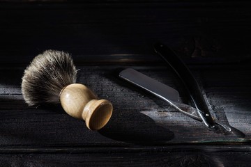 Straight razor and shaving brush on a luxury wooden background