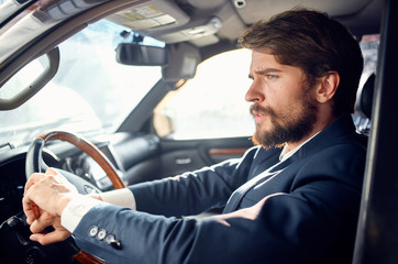 business man with a beard in a suit driving a car