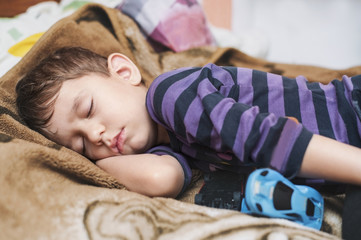 Little boy sleeps sweetly in bed at home