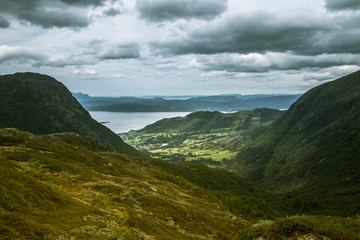 Fototapeta premium A beautiful autumn landscape of mountains in Folgefonna National park with fjord far in the distance. Fall scenery of southern Norway, Autumn colors in overcast day.
