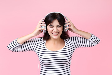 Young woman with headphones on pink background