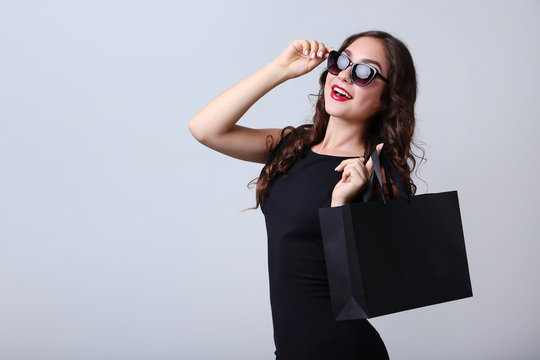 Happy woman with shopping bag on grey background