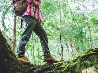 Hiking man with trekking boots standing on the bright green moss passage trail in forest