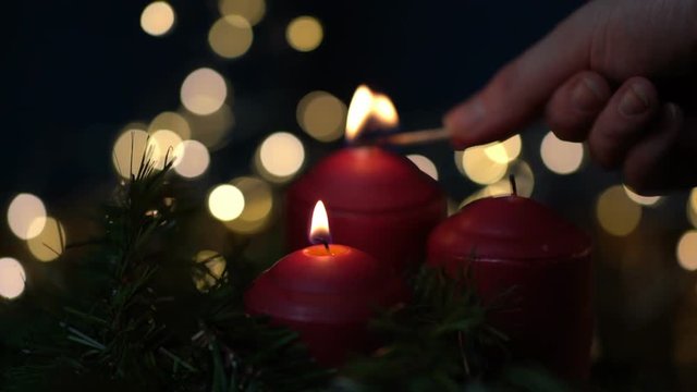 Woman hand lighting red candle with a match