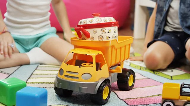 kids play with yellow tipper truck and toy pan in children room