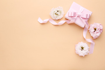 Gift box with ribbon and eustoma flowers on beige background