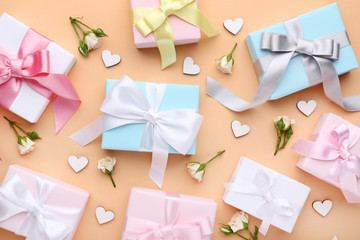 Gift boxes with rose flowers and white hearts on beige background