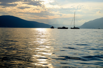 Sailboat in the sea in the evening sunlight over beautiful big mountains background, luxury summer adventure, active vacation in Tivat, Montenegro