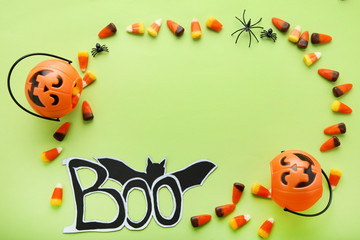 Halloween candy corns and pumpkin bucket on green background