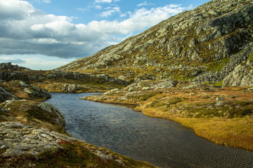 A beautiful autumn mountain landscape with a small lake. Natural scenery in Norwegian mountains. Small water pond in mountains.