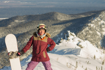 Snowboarder girl freerider is standing in the snowy mountains in winter under the clouds