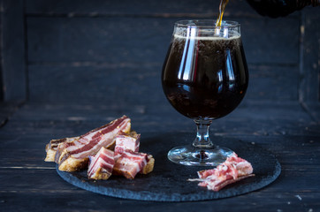 A glass of dark beer without frothy. Dried pork ribs.