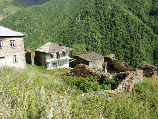 Fototapeta na wymiar Antiche case in discesa nelle montagne dell'alto Caucaso in Georgia.
