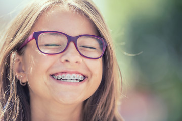 Portrait of a happy smiling teenage girl with dental braces and glasses