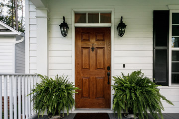 Fototapeta na wymiar Brown Wood Front Door of a White Siding Southern House