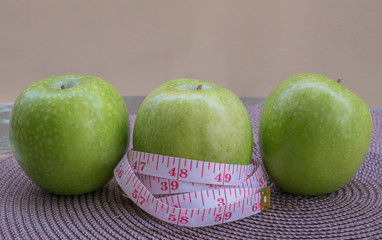 Measuring tape wrapped around a green apple as a symbol of diet.