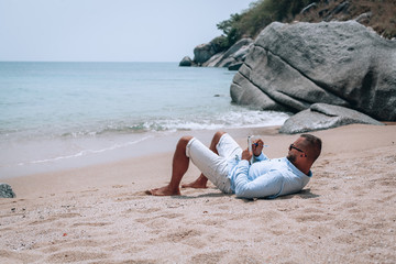 a young businessman in sunglasses, blue shirt and shorts writes in a notebook