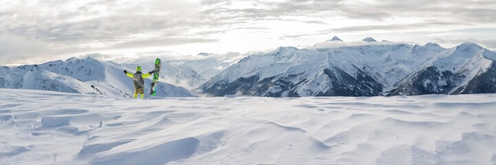 panorama snowboarder freerider is standing in the snowy mountains in winter under the clouds