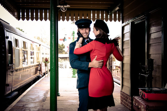 Attractive couple dance on railway station platform with portable record player