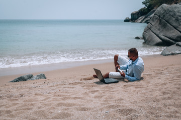 a young businessman in sunglasses, blue shirt and shorts writes in a notebook