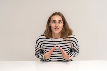 Portrait of a beautiful brunette girl on a white background at the table with different emotions.