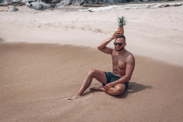 The guy is resting on the beach in Thailand, in the hands of pineapples